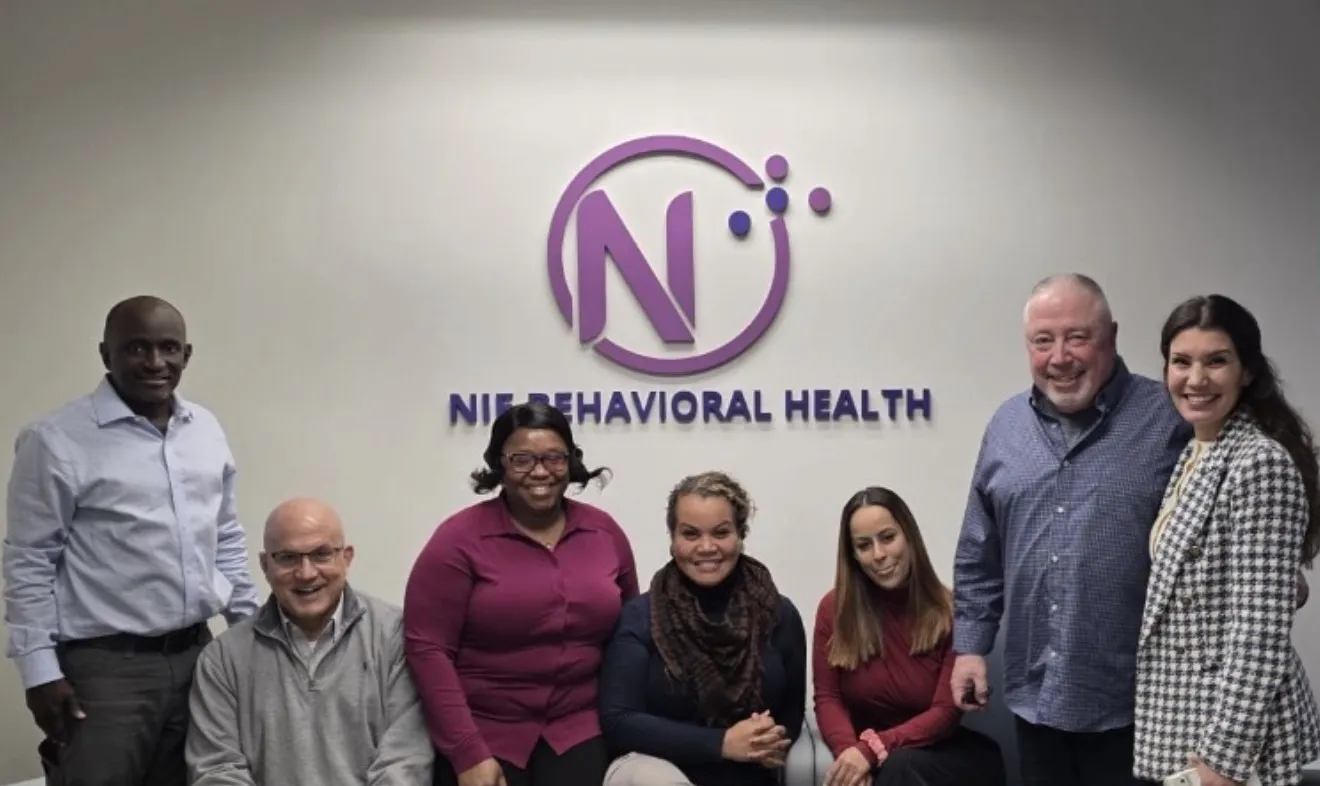 NIE Behavioral Health team in front of the office logo